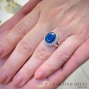 Anel Estilo Lady Di ou Princesa Daiana em Ouro 18k cravejados de Brilhante com 1 Safira Azul Lapidada.